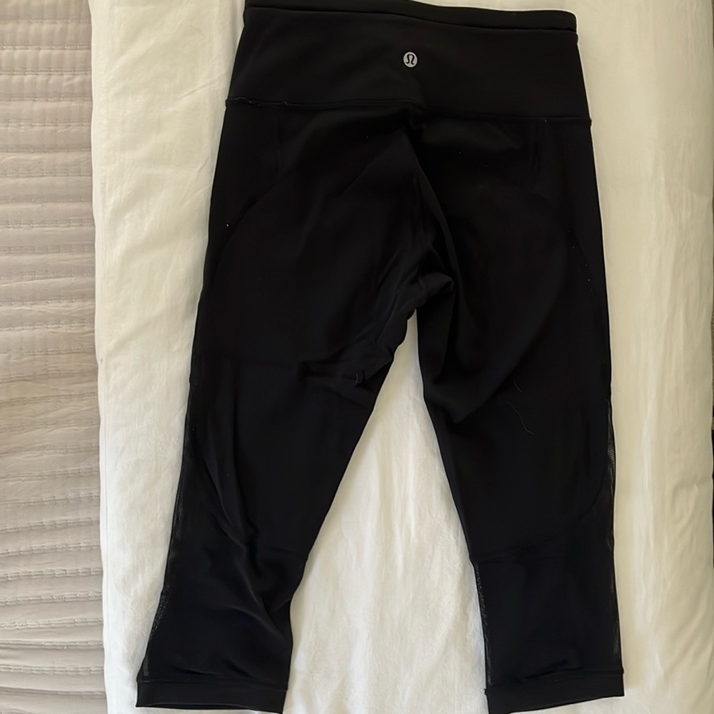 Black Lululemon cropped leggings with mesh on the bottom.